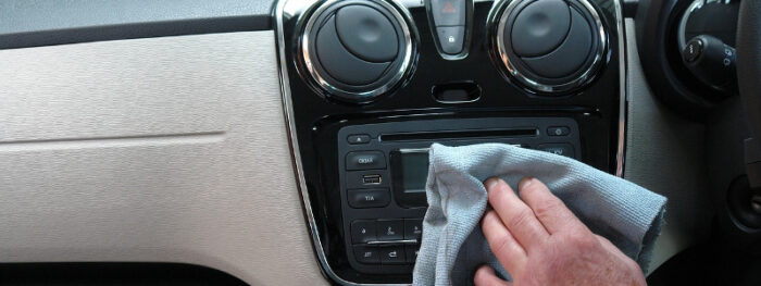 man using a microfibre cloth to clean car interior