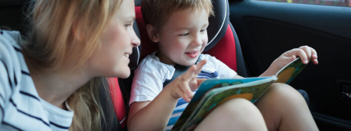 parent and child reading a book in the car
