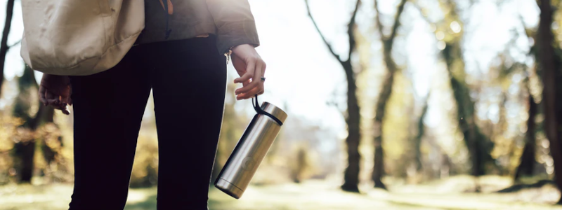 woman with a reusable water bottle in the woods