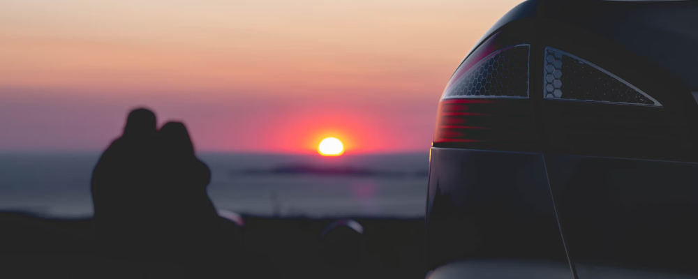 couple at sunset next to car