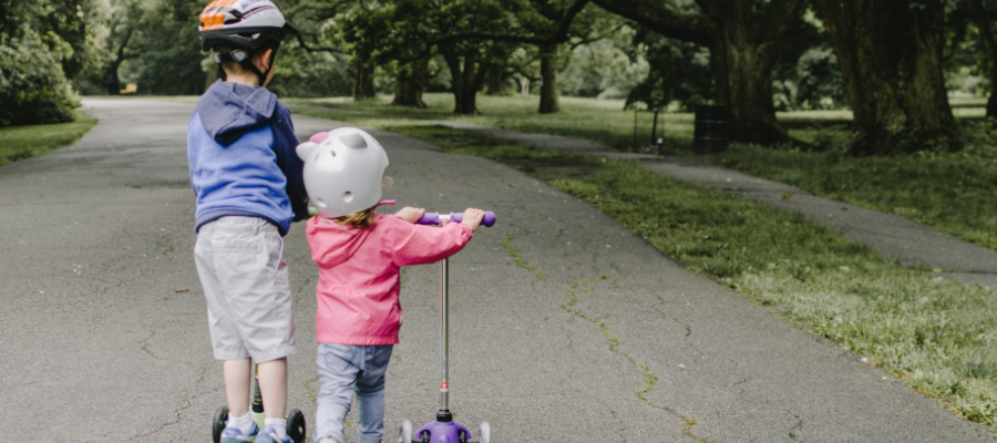 Kids entertainment on road trip - boy and girl child playing on scooters
