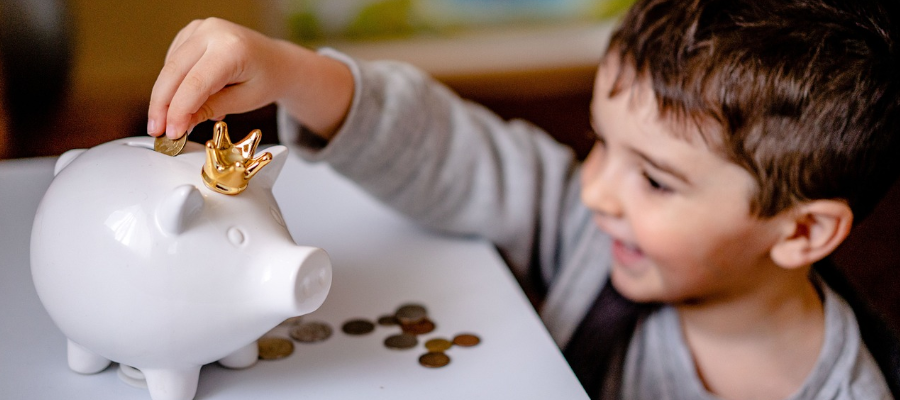 Child putting money in piggy bank saving money