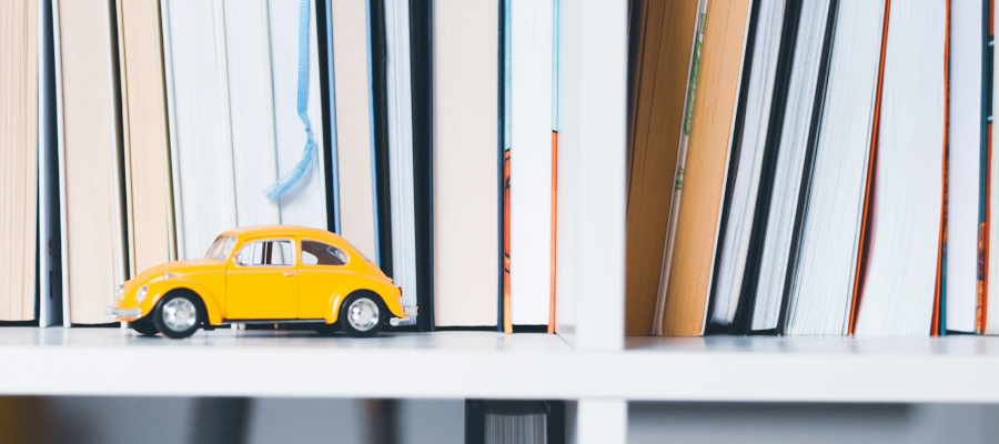 Toy car sitting on a bookshelf with books